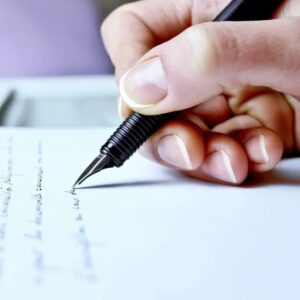A person writing on paper with a pen.