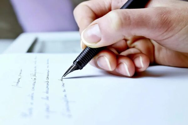 A person writing on paper with a pen.