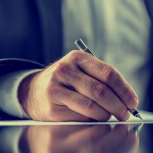 A person writing on paper with a pen.